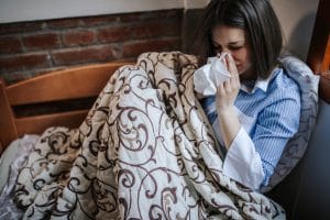 Woman with allergy symptoms resting on couch.