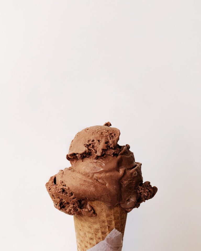 A scoop of chocolate ice cream on a waffle cone.