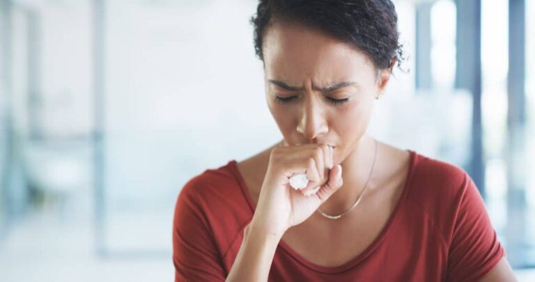 Woman coughing at her desk.