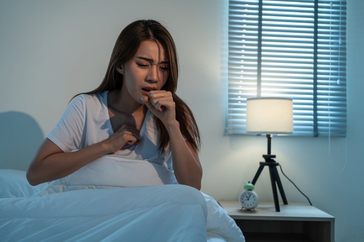 Woman coughing in bed at night.